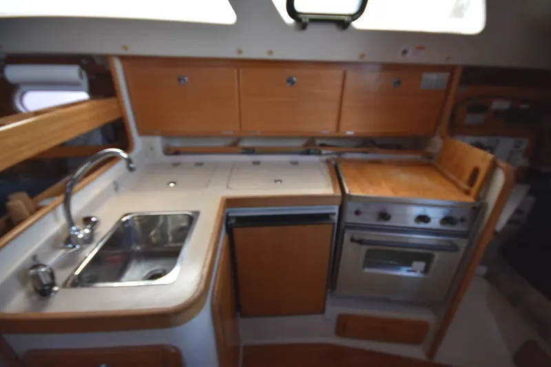 Slide: The Image of 2001 Catalina 310 yacht kitchen with sink, stove, and wooden cabinetry. - 59