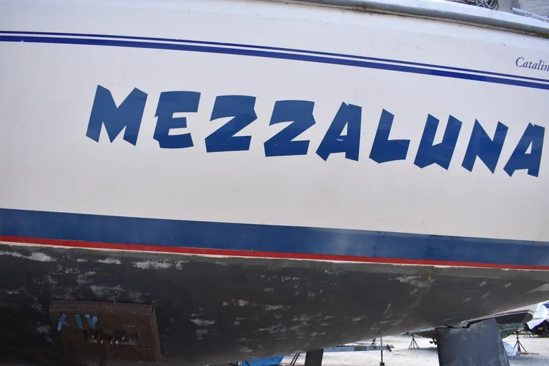 Slide: The Image of Catalina 310 sailboat named "Mezzaluna," 2001 model, with blue and red stripes. - 6