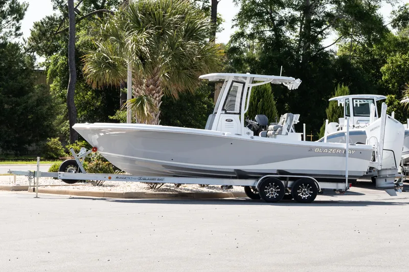 The Image of 2026 Blazer Bay Makaira 2600 boat on trailer, parked outdoors with trees in background. - 1