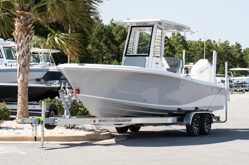 Slide: The Image of 2026 Blazer Bay Makaira 2600 boat on trailer, parked near palm tree. - 2