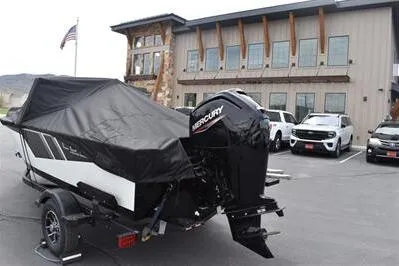 Slide: The Image of 2026 Lowe Fishing Machine 1675 WT boat with Mercury engine, parked outside a modern building. - 38