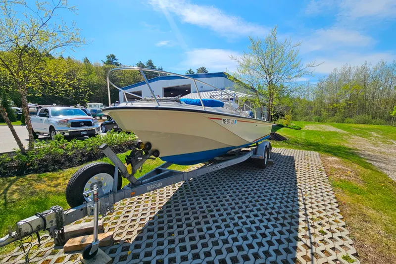 Slide: The Image of 1990 Boston Whaler OUTRAGE CUDDY boat on trailer, parked outdoors under clear blue sky. - 4
