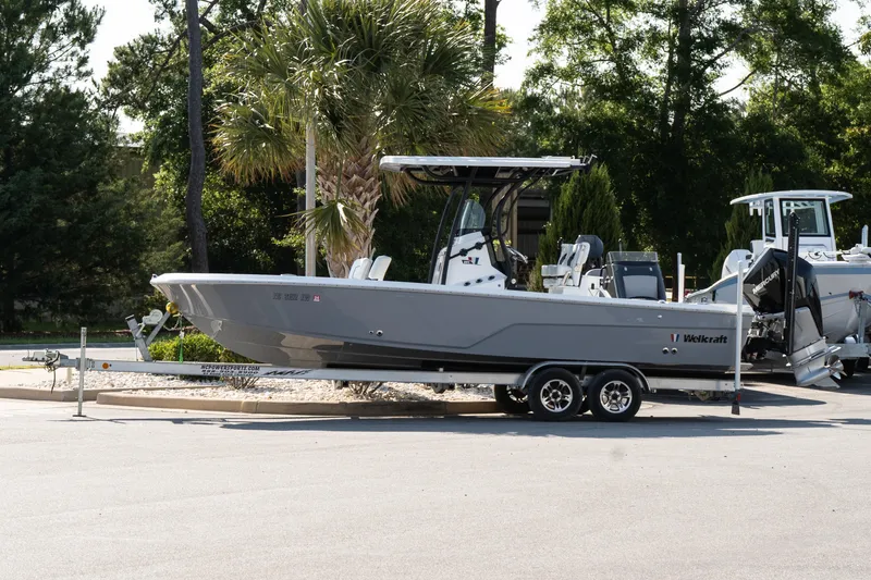 The Image of 2022 Wellcraft 241 Bay boat on trailer, parked outdoors with trees in background. - 1