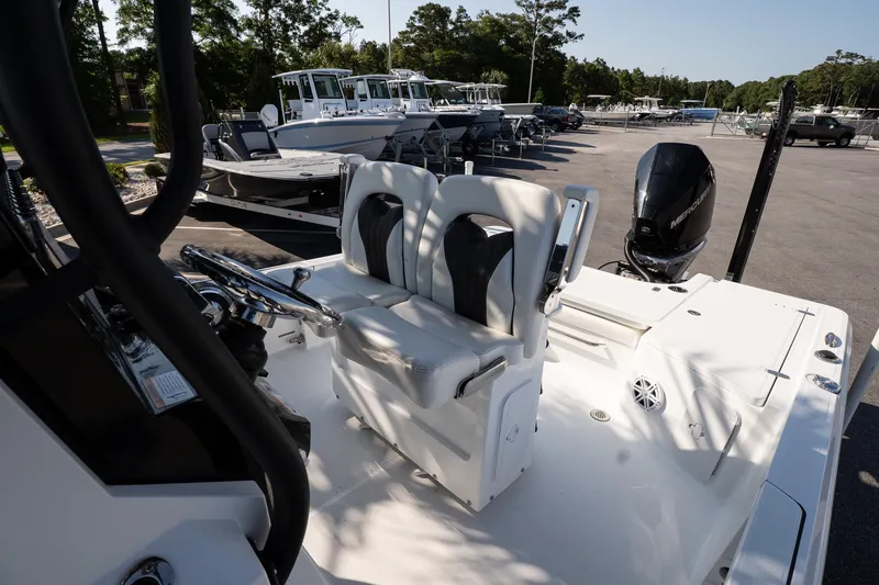 Slide: The Image of 2022 Wellcraft 241 Bay boat interior with dual seats and steering wheel, parked outdoors. - 13