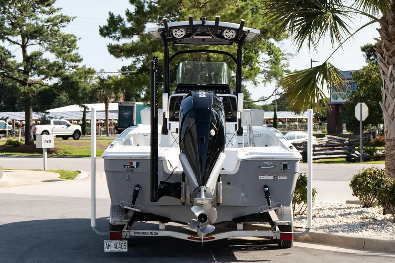 Slide: The Image of 2022 Wellcraft 241 Bay boat on trailer, parked outdoors with trees and palm nearby. - 5