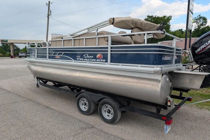 Slide: The Image of 2023 Sun Tracker Fishin' Barge 20 DLX pontoon boat on trailer, parked outdoors. - 31