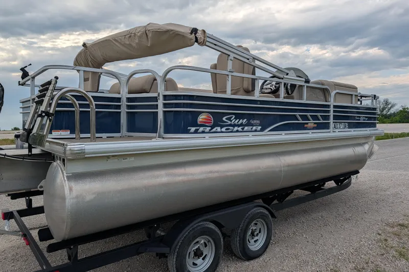 Slide: The Image of 2023 Sun Tracker Fishin' Barge 20 DLX pontoon boat on trailer under cloudy sky. - 33
