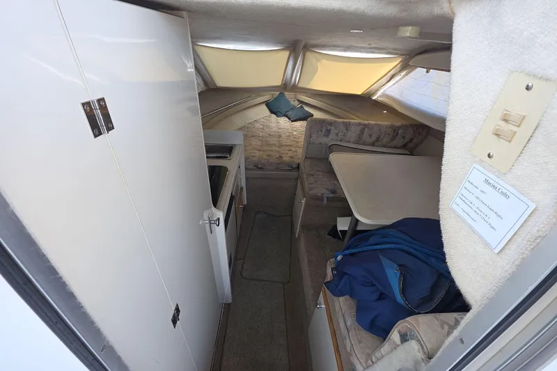 Slide: The Image of Interior of 1999 Bayliner 2452 Ciera Express, featuring compact cabin with seating and kitchenette. - 13