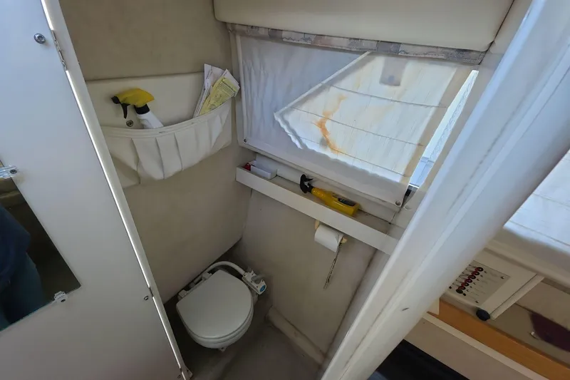 Slide: The Image of 1999 Bayliner 2452 Ciera Express boat bathroom with toilet and cleaning supplies. - 6