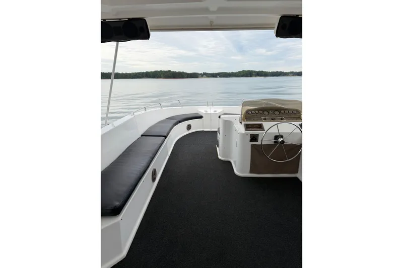 Slide: The Image of 2004 Sumerset 18x96 houseboat interior with steering wheel and seating, overlooking calm waters. - 15