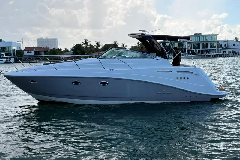 The Image of 2007 Rinker 350 Express Cruiser on water, with modern waterfront homes in background. - 0
