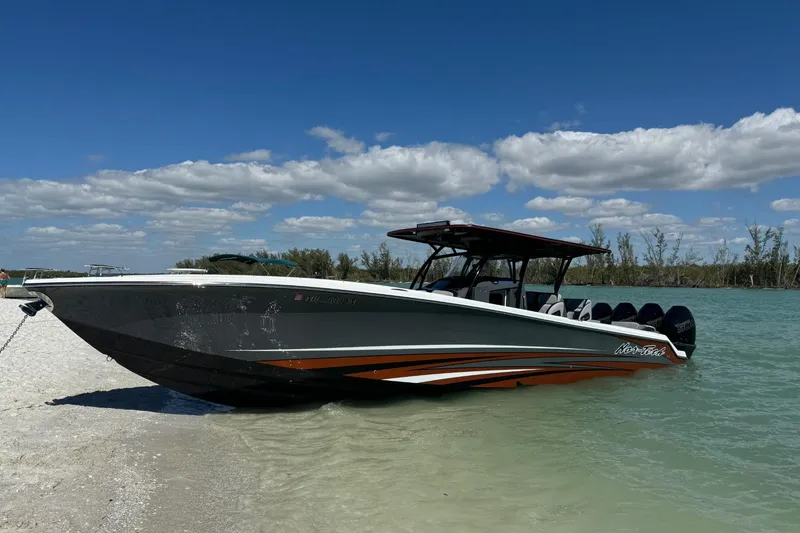 The Image of 2024 Nor-Tech 390 Sport Center Console boat on sandy shore under blue sky. - 0