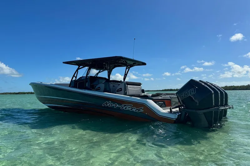 Slide: The Image of 2024 Nor-Tech 390 Sport Center Console boat on clear turquoise water under blue sky. - 1