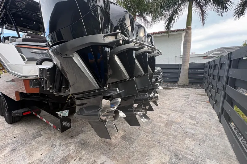 Slide: The Image of 2024 Nor-Tech 390 Sport Center Console with powerful outboard engines, parked on a paved driveway. - 34