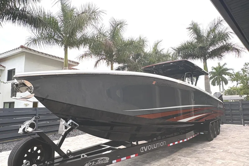 Slide: The Image of 2024 Nor-Tech 390 Sport Center Console boat on trailer, surrounded by palm trees. - 4