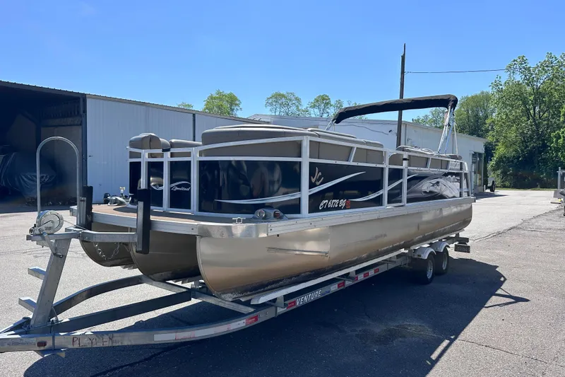Slide: The Image of 2015 JC 24 Tri-Toon pontoon boat on trailer, parked outdoors. - 1