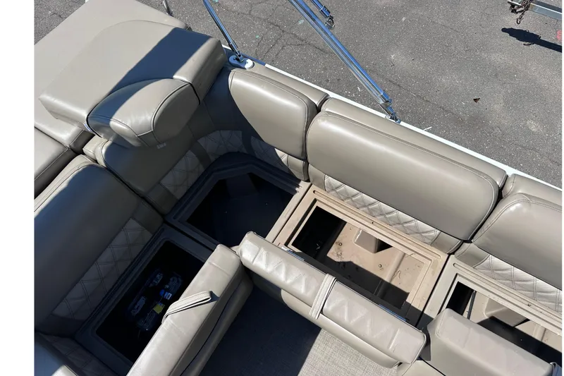 Slide: The Image of 2015 JC 24 Tri-Toon boat interior with open storage compartments and beige seating. - 11