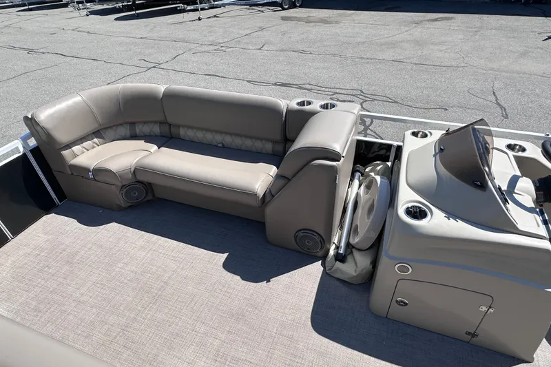 Slide: The Image of 2015 JC 24 Tri-Toon boat interior with beige seating and helm, featuring cup holders. - 18