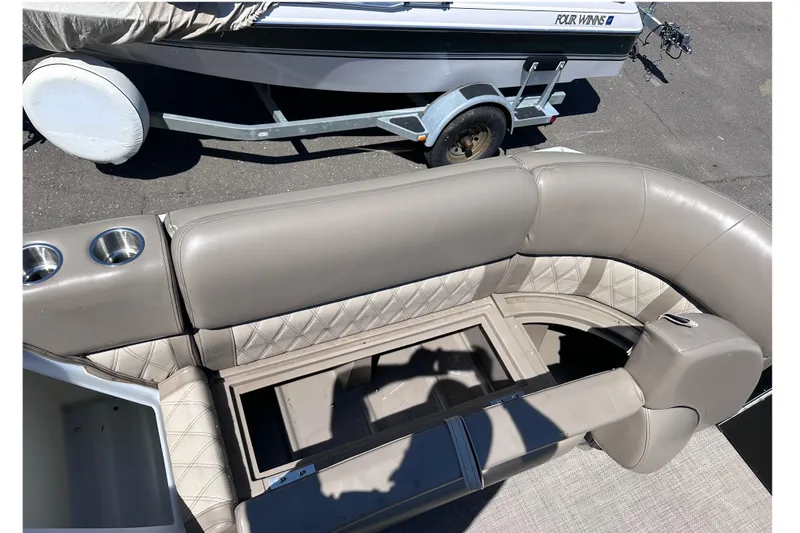 Slide: The Image of 2015 JC 24 Tri-Toon boat interior with beige seating and cup holders. - 21