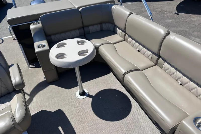 Slide: The Image of 2015 JC 24 Tri-Toon boat interior with beige seating and round table. - 9