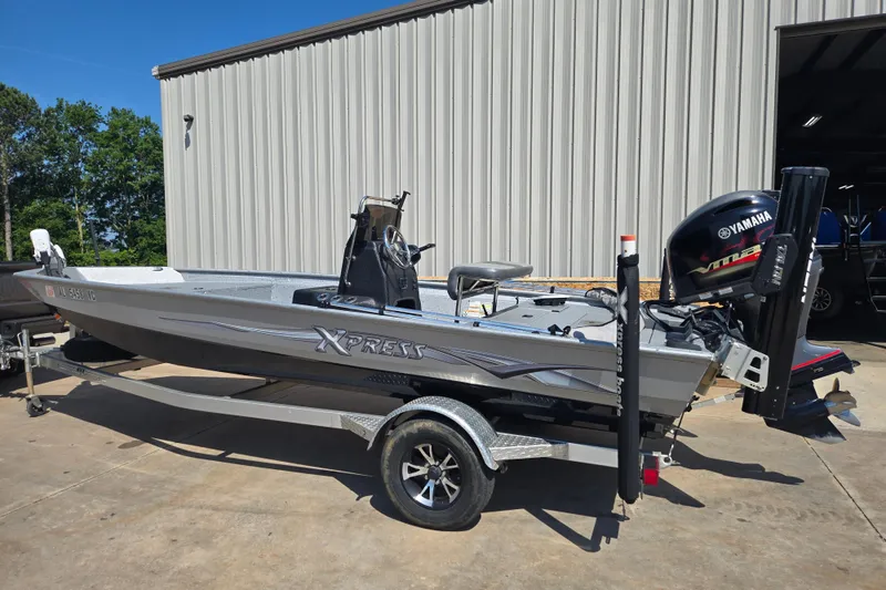 Slide: The Image of 2019 Xpress SW20B boat with Yamaha engine on trailer, parked outside a metal building. - 1