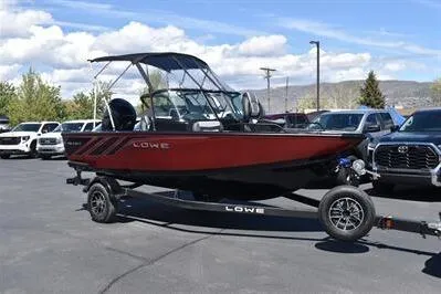 Slide: The Image of 2026 Lowe Fish & Ski 1700 boat on trailer, parked outdoors, with cars in the background. - 1