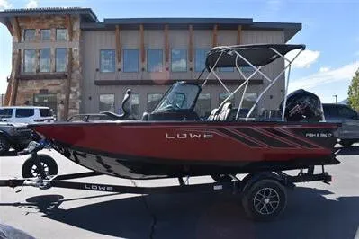 Slide: The Image of 2026 Lowe Fish & Ski 1700 boat, red and black, parked outdoors. - 10