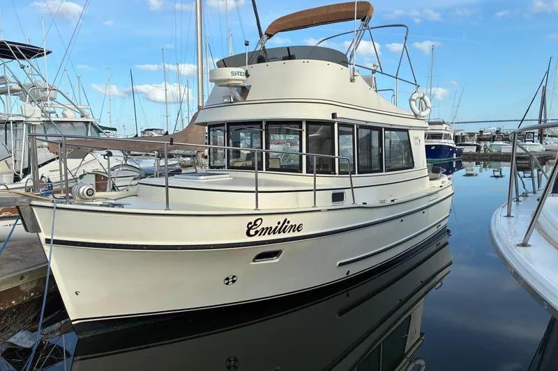 The Image of 2003 Camano Troll boat named Emiline docked in a marina, reflecting on calm water. - 0