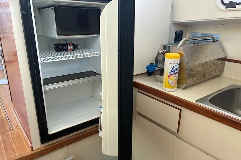 Slide: The Image of 2003 Camano Troll boat kitchen with open fridge, sink, and cleaning supplies. - 11