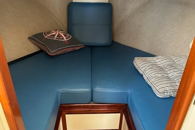 Slide: The Image of Cozy cabin interior of 2003 Camano Troll boat with blue cushions and nautical-themed pillow. - 12
