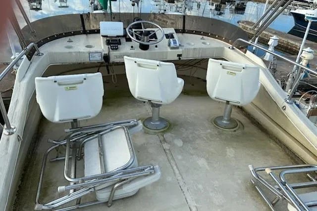Slide: The Image of 2003 Camano Troll boat cockpit with three white chairs and steering controls. - 2