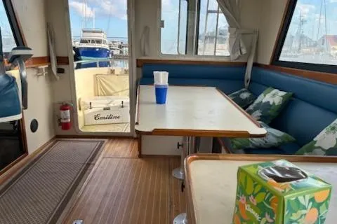 Slide: The Image of Interior of a 2003 Camano Troll boat with seating and table, docked at a marina. - 8