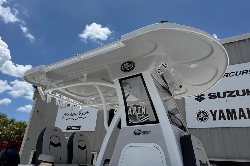 Slide: The Image of 2026 Sea Pro 262 Offshore boat with T-top, parked near dealership signs under blue sky. - 10
