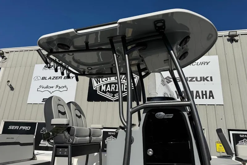 Slide: The Image of 2026 Sea Pro 250 Bay boat with T-top and seating, displayed at a marine dealership. - 4