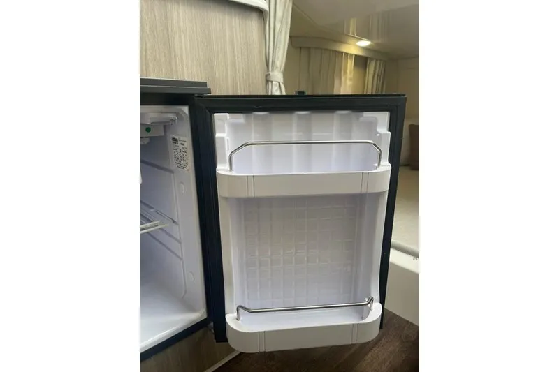Slide: The Image of Open mini fridge inside 2020 Regal 28 Express boat cabin, showcasing interior storage space. - 15