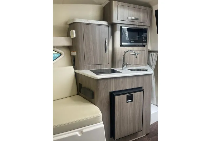 Slide: The Image of Compact kitchen area in a 2020 Regal 28 Express boat, featuring modern cabinetry and appliances. - 21