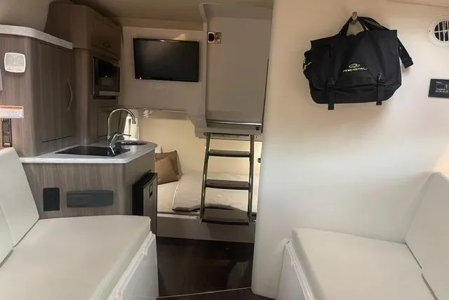 Slide: The Image of Interior of 2020 Regal 28 Express boat with kitchenette, seating, and TV. - 23