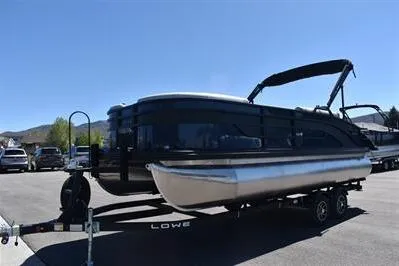 Slide: The Image of 2026 Lowe SF 212 Sport Fish pontoon boat on trailer, parked outdoors. - 6