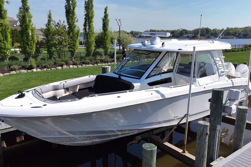 The Image of 2024 Boston Whaler 350 Realm boat docked near lush greenery and waterfront. - 0