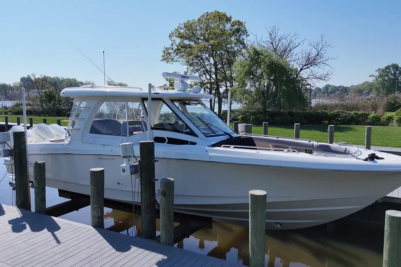 The Image of 2024 Boston Whaler 350 Realm boat docked by a scenic waterfront. - 1