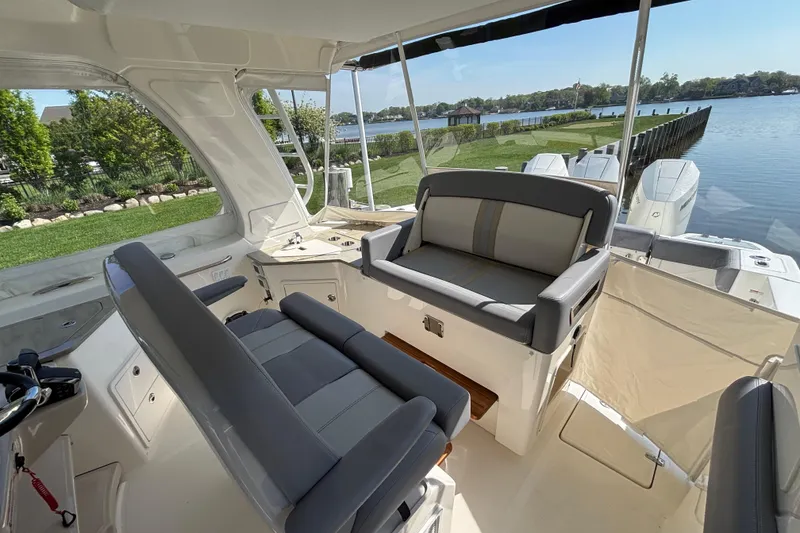 Slide: The Image of 2024 Boston Whaler 350 Realm interior with seating, overlooking serene waterfront. - 10