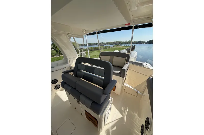 Slide: The Image of 2024 Boston Whaler 350 Realm interior with seating, overlooking a serene waterfront. - 11