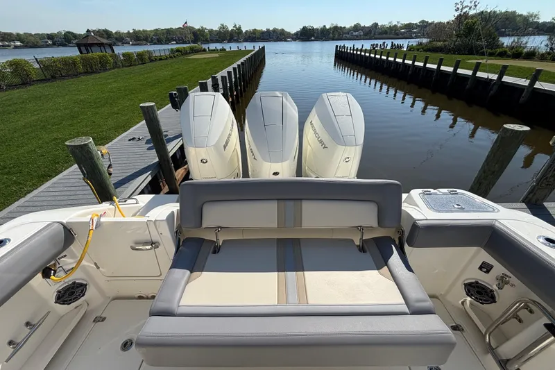 Slide: The Image of 2024 Boston Whaler 350 Realm boat with triple Mercury engines docked by a serene lake. - 12