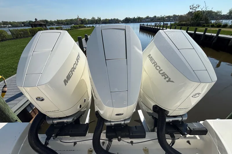 Slide: The Image of Triple Mercury outboard engines on a 2024 Boston Whaler 350 Realm boat by the water. - 13