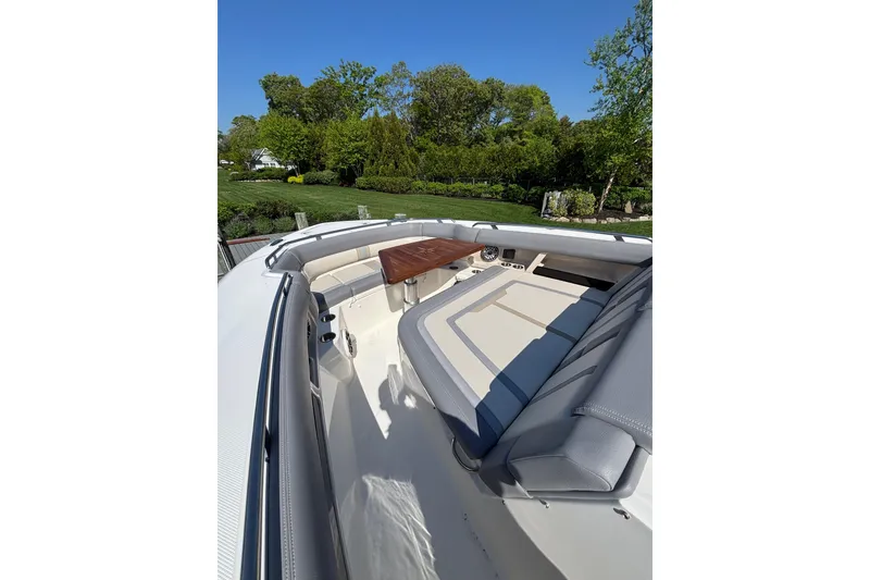 Slide: The Image of 2024 Boston Whaler 350 Realm boat interior with cushioned seating and wooden table. - 20