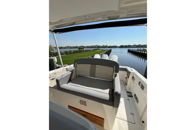 Slide: The Image of 2024 Boston Whaler 350 Realm boat with seating, docked by a scenic waterfront. - 24