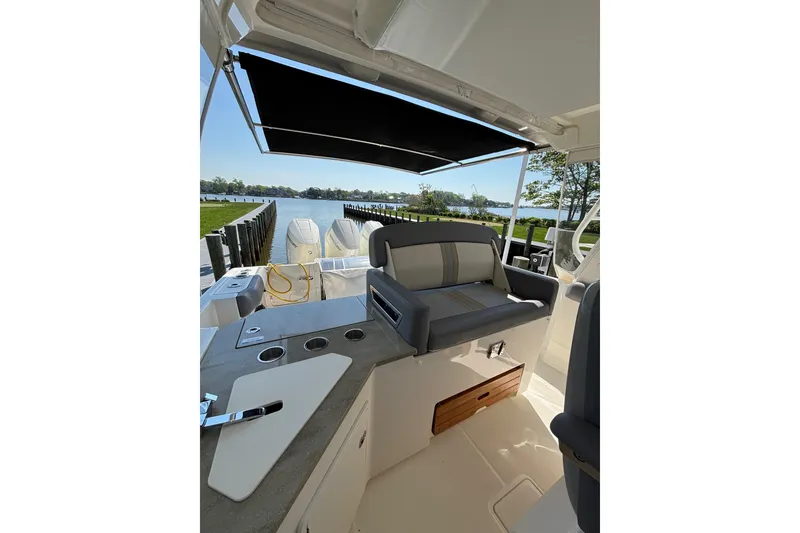 Slide: The Image of 2024 Boston Whaler 350 Realm interior with seating, countertop, and scenic waterfront view. - 25