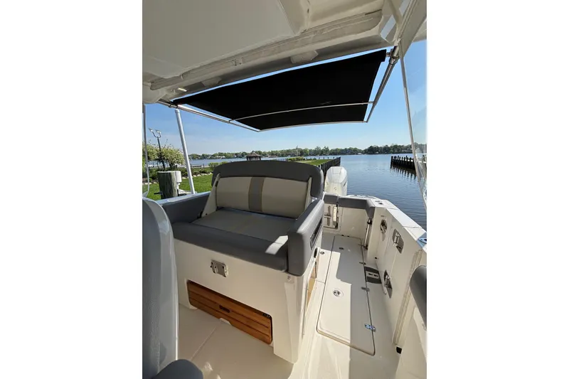 Slide: The Image of 2024 Boston Whaler 350 Realm boat interior with seating and canopy, docked by a serene lake. - 26