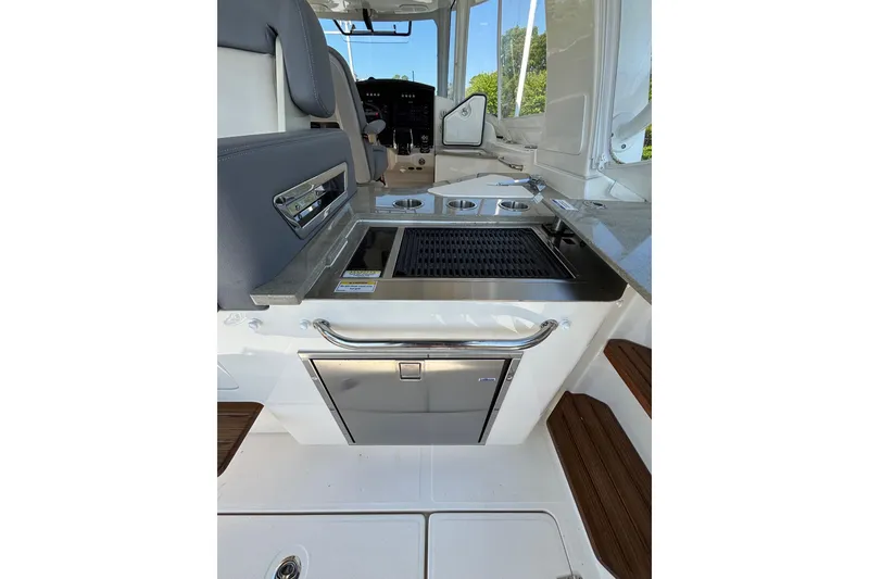 Slide: The Image of 2024 Boston Whaler 350 Realm boat interior with grill and seating area. - 29