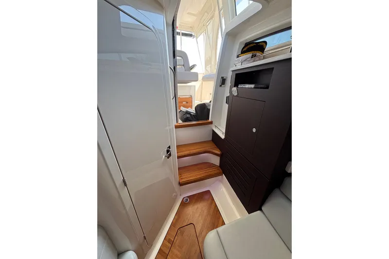 Slide: The Image of Interior of 2024 Boston Whaler 350 Realm, featuring wooden steps and modern cabinetry. - 35